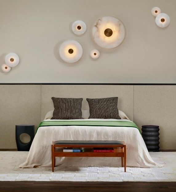 a bed with pillows and lights on the wall above it