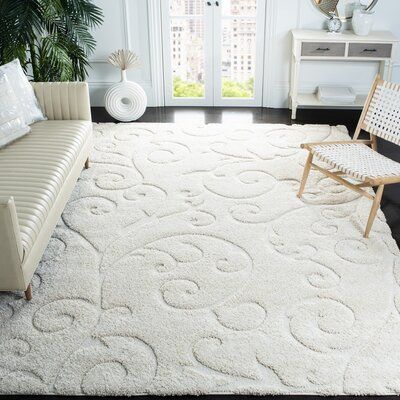 a living room with white furniture and rugs