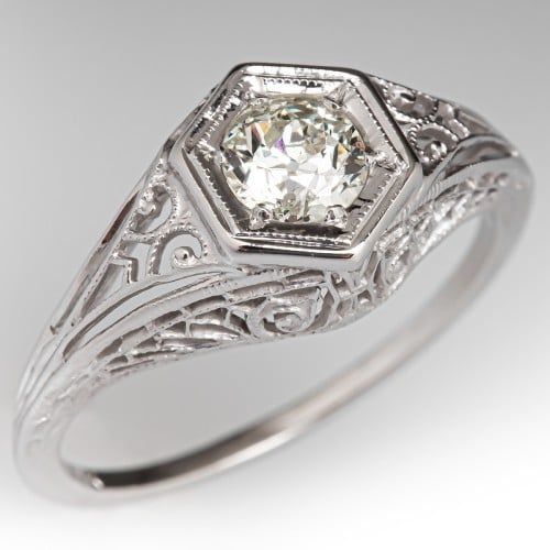 an antique style diamond ring with filigrees on the sides and center stone