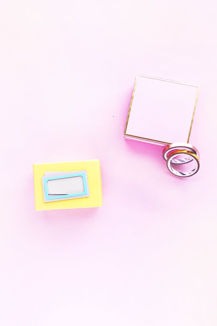 two wedding rings sitting on top of a pink surface next to a box with a ring in it