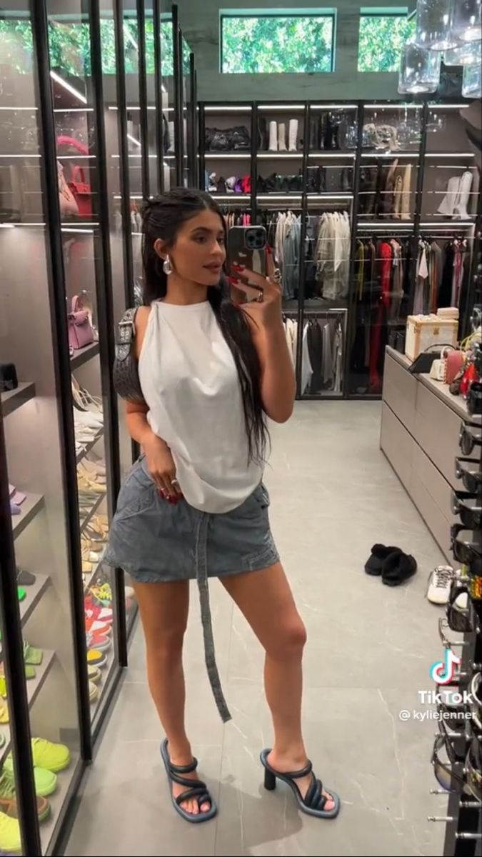 a woman is taking a selfie in a clothing store with her phone up to her ear