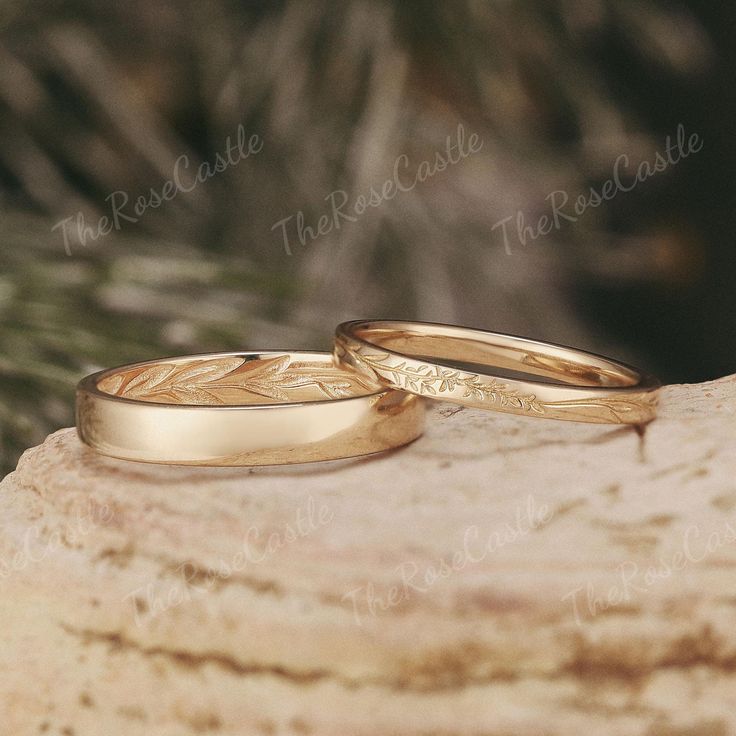 two gold wedding rings sitting on top of a piece of rock next to each other