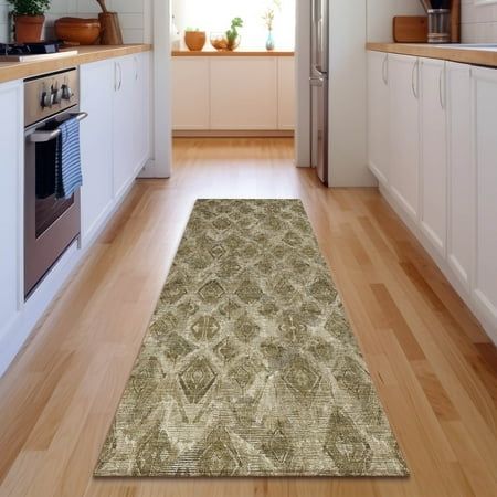 a kitchen area with wooden floors and white cabinets, along with a rug on the floor