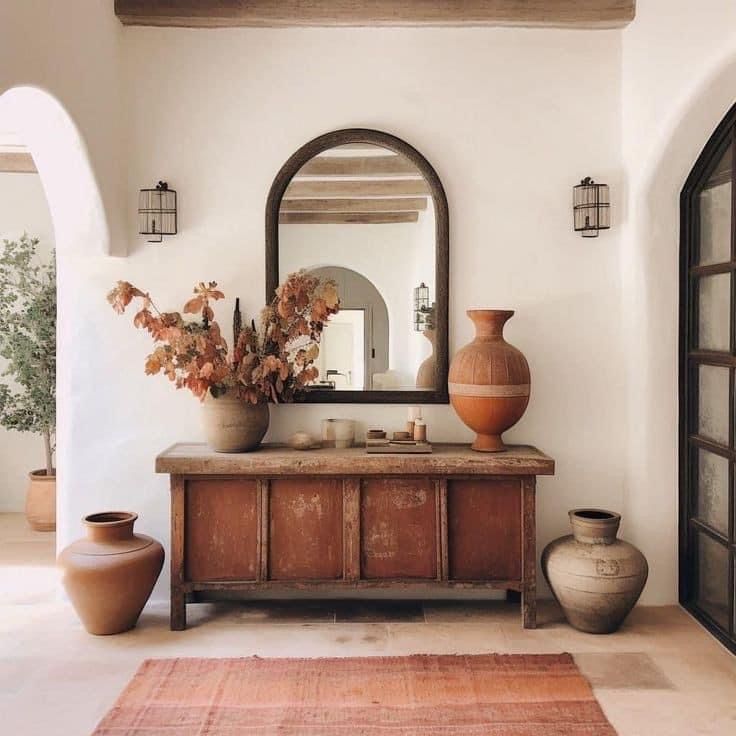 a large mirror sitting above a wooden dresser next to vases on top of a rug