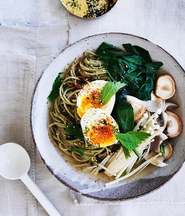 a white bowl filled with noodles, spinach and hard boiled eggs on top of it