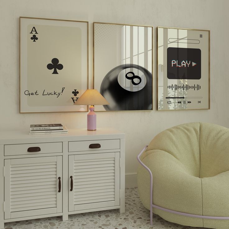 two framed pictures hang on the wall above a white cabinet with drawers and a lamp