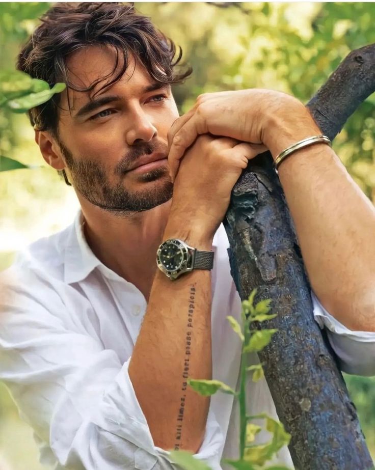 a man leaning on a tree branch wearing a watch