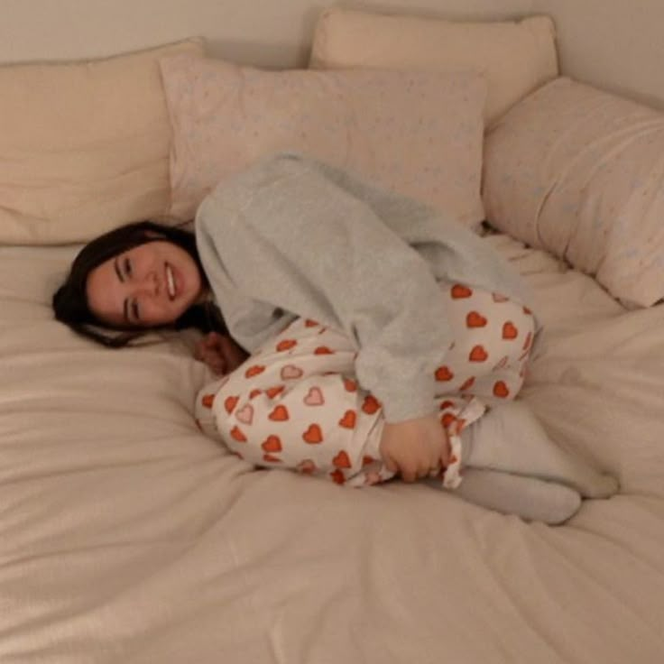 a woman laying on top of a bed in pajamas