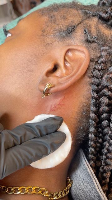 a woman is getting her hair done with an ear piercing and gloves on top of her head