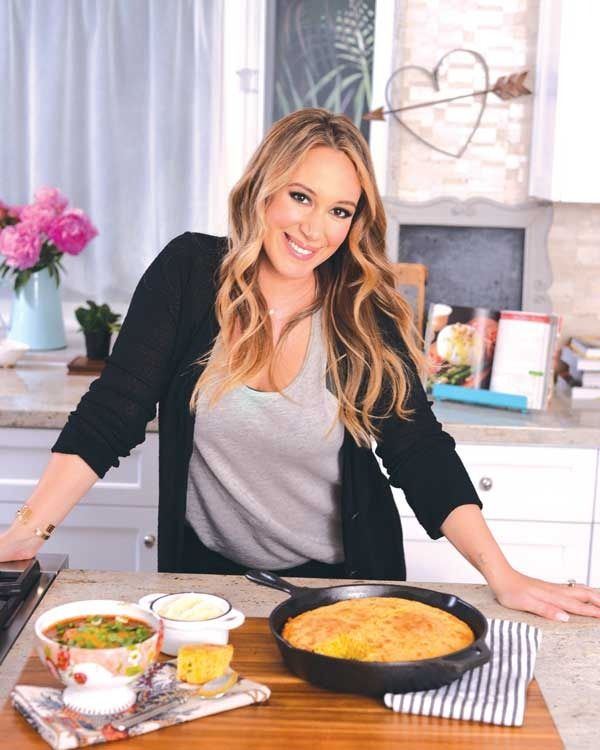 a woman standing in front of a pan of food on top of a kitchen counter