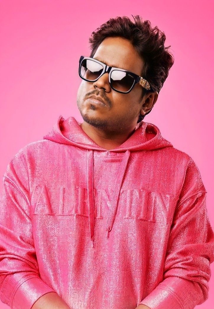 a man wearing sunglasses and a pink hoodie with his arms crossed in front of him