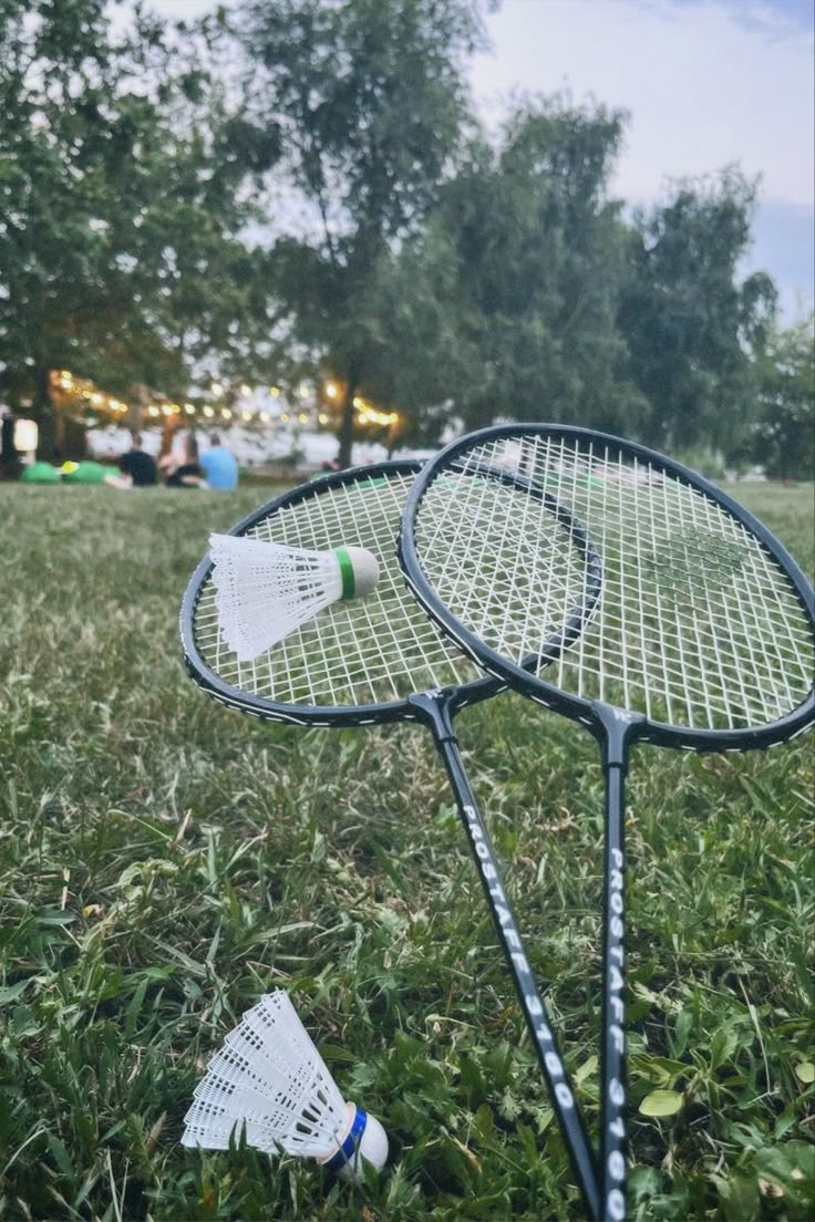 two tennis racquets sitting in the grass with one broken on it's side