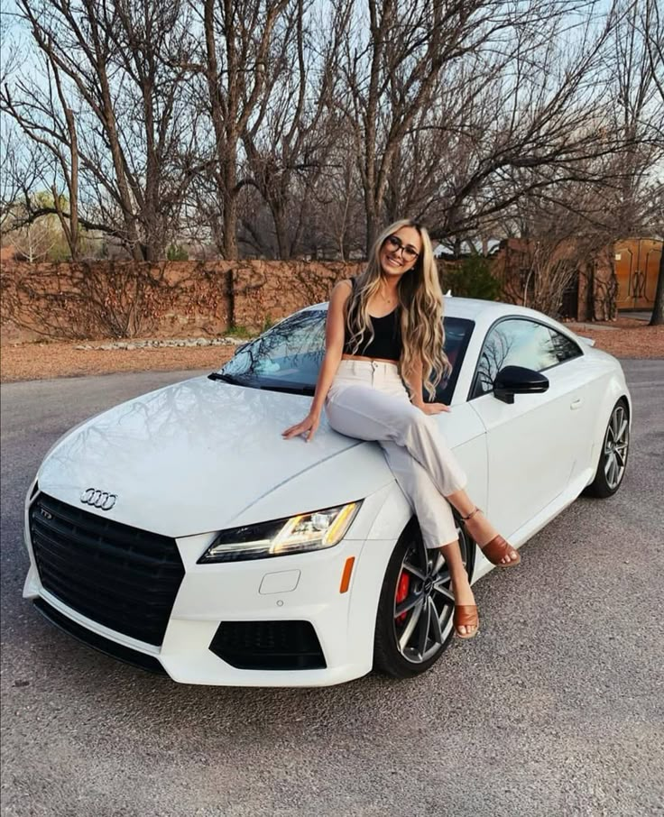 a woman sitting on top of a white car