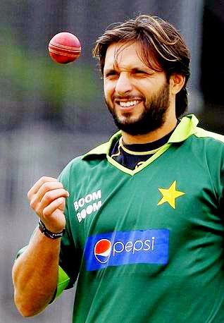 a man in green jersey throwing a red ball on top of his head and smiling at the camera