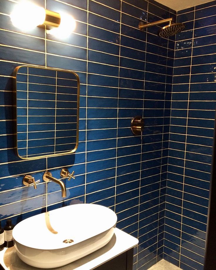 a blue tiled bathroom with a sink and mirror