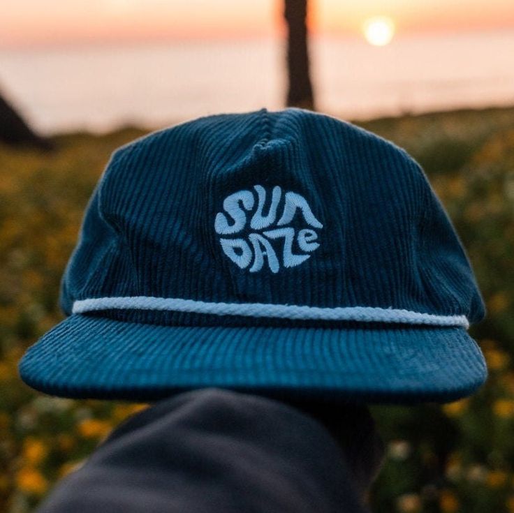 The Dark Blue Corduroy SunDaze Circle 5-panel hat effortlessly captures the essence of the 80's surf era, combining classic design elements with a modern twist. Crafted from high-quality, deep blue corduroy fabric, this cap showcases a distinctive circular emblem on its front panel, paying homage to the iconic sun-soaked days of the 1980s surfing culture. The dark blue hue of the corduroy resembles the vastness of the oceans waves coming in from the horizon, while simultaneously giving a nod to the nostalgic vibes of the era it draws inspiration from. The 5-panel construction of the cap ensures a comfortable and snug fit, suitable for various head shapes and sizes. The design incorporates the signature snap-back feature, allowing for easy adjustment to achieve the perfect fit. This functio Surf Hats, Corduroy Hat, 5 Panel Hat, Blue Corduroy, Vintage Surf, Panel Hat, The 80's, Cute Hats, Cool Hats