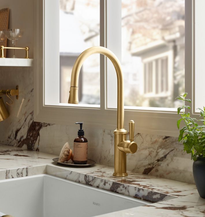 a kitchen sink with gold faucet and soap dispenser