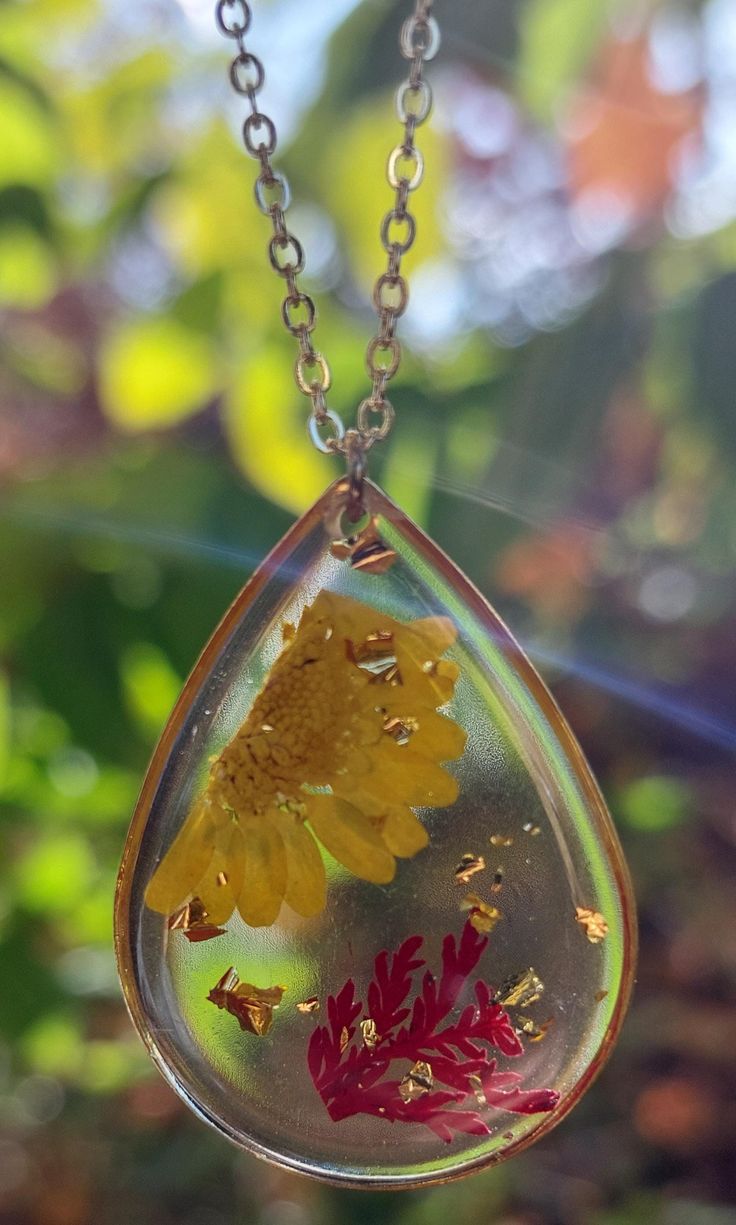 a yellow flower in a tear shaped glass pendant