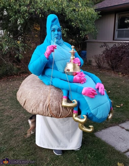 an inflatable blue man sitting on top of a mushroom with a gold cup