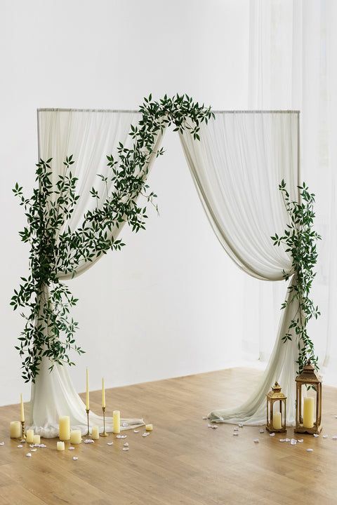 an arch decorated with greenery and candles is set up on the floor for a wedding ceremony