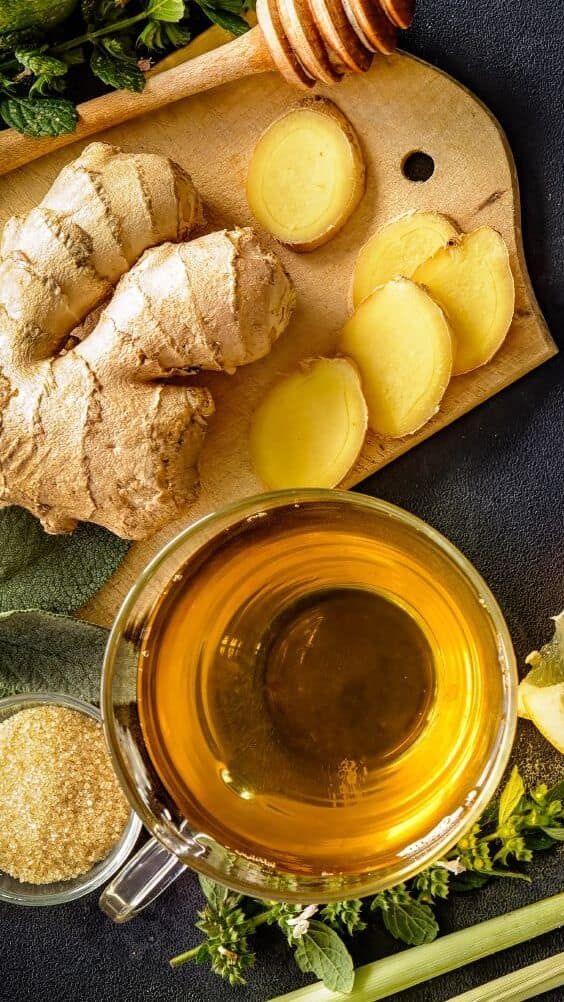 a cutting board topped with sliced up potatoes next to a cup of tea and honey