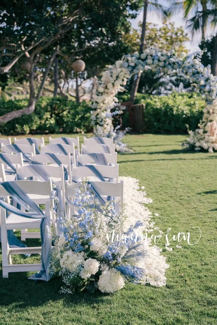 a row of white chairs sitting on top of a lush green field