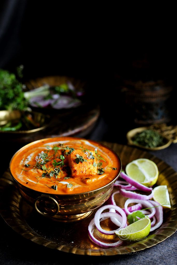 a bowl of soup on a plate with onions, limes and cilantro