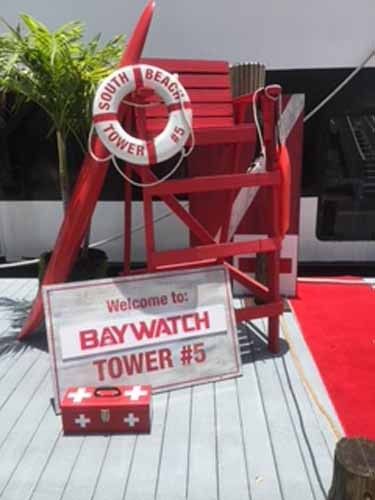 a red chair sitting on top of a wooden floor next to a sign that says welcome to baywatch tower 3