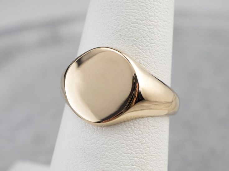 Smooth and simple, this vintage signet ring is crafted of rich yellow gold with room in the center for a family crest or one's initials! This is a perfectly polished piece with no decoration or motifs to mar the amazing finish. Market Square Jewelers works with one of the finest hand engravers in the northeast. With over 30 years of experience, our engraver hand carves lettering, monograms, crests, or patterns in period-specific styles. Choose from our many monogram options shown in the listing Gold Polished Finish Rounded Signet Ring, Gold Polished Finish Signet Ring, Classic Oval Signet Ring With Polished Finish, Classic Yellow Gold Oval Signet Ring, Gold Polished Signet Ring, Classic Oval Yellow Gold Signet Ring, Classic Oval Ring With Polished Edges, Formal Oval Signet Ring With Polished Edges, Timeless Oval Signet Ring With Polished Finish