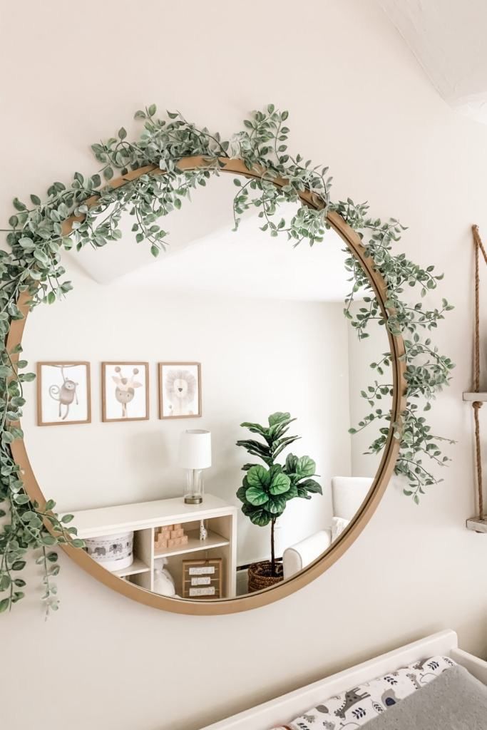 a round mirror hanging on the wall above a crib with a plant in it