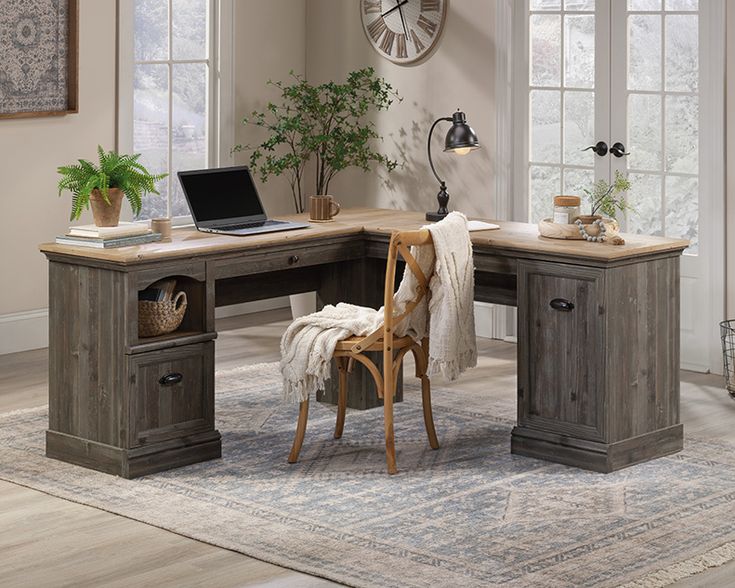 a desk with a chair and laptop on top of it in front of two windows