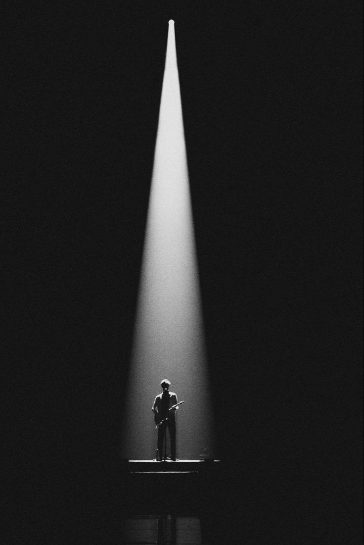 a person standing in the middle of a stage with a spotlight coming from behind them