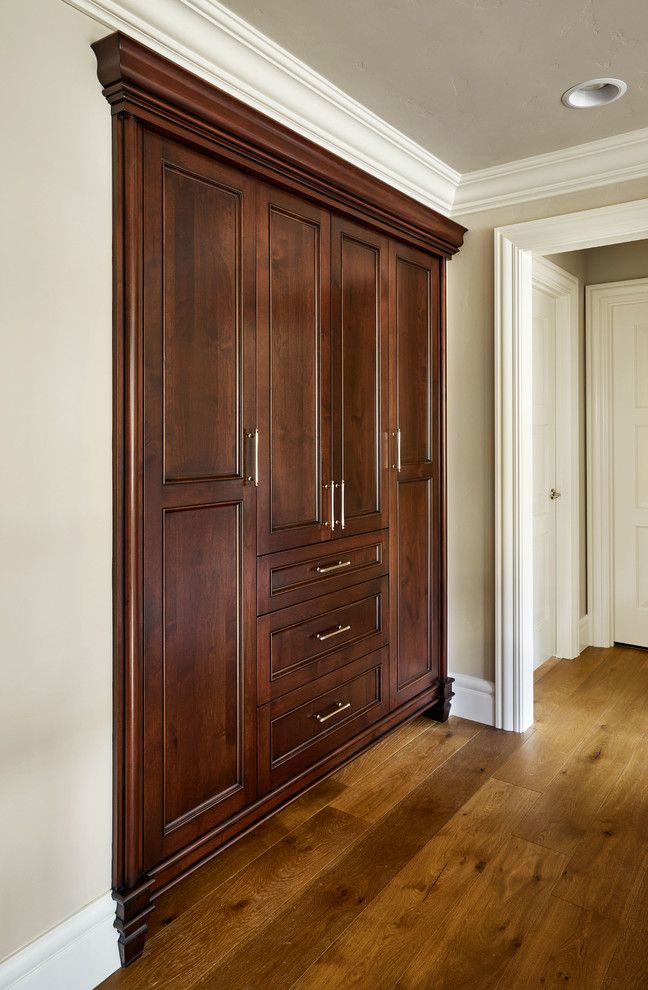 an empty room with wooden cabinets and hard wood flooring, along with white walls