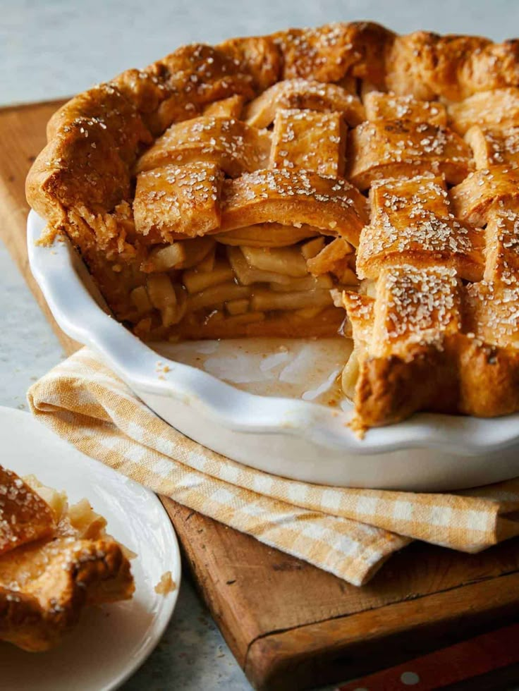 an apple pie is on a white plate and next to two plates with desserts