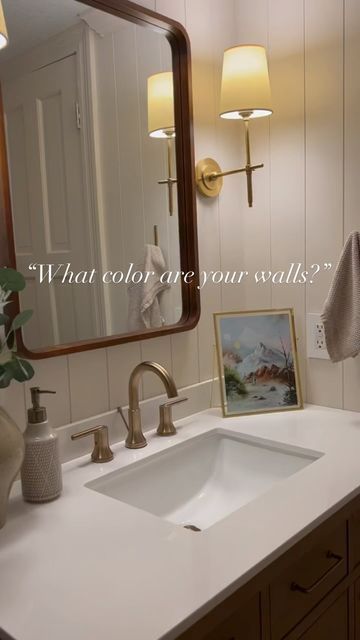 a bathroom sink with a mirror above it and a painting on the wall behind it