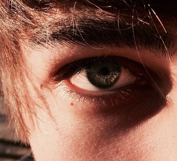 a close up of a person's eye with long hair on top of his head