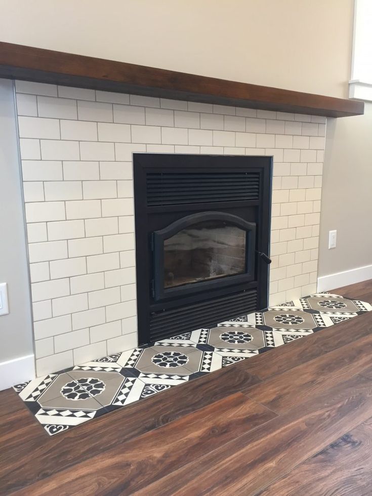 a fireplace with white and black tiles on the floor