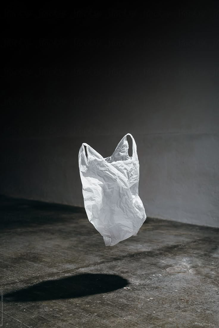 a white plastic bag floating in the air by an empty concrete floor for use as a background