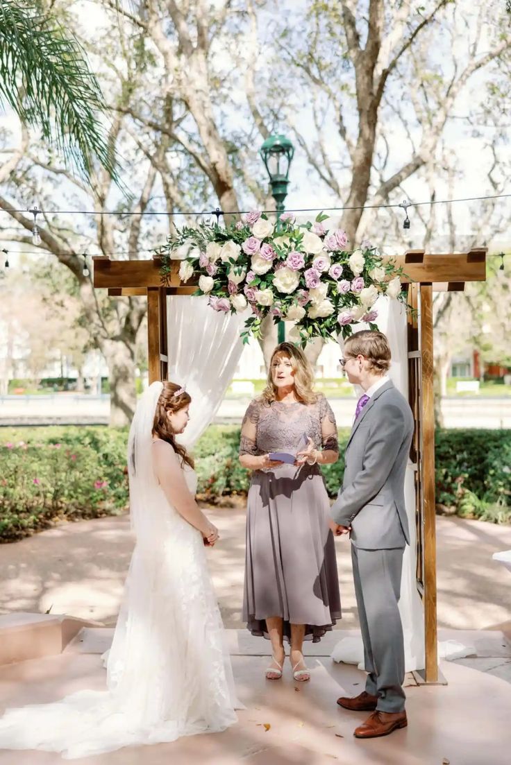 a couple getting married under a floral covered arch