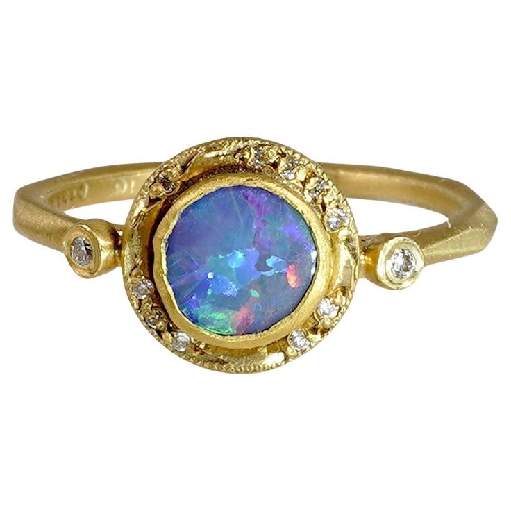 a gold ring with an opal and diamond set in the center, on a white background