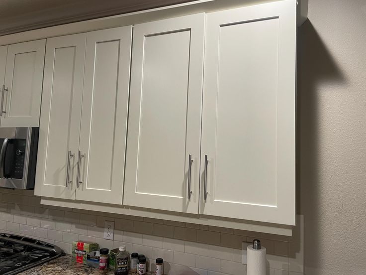 a kitchen with white cupboards and appliances on the counter top in front of an oven