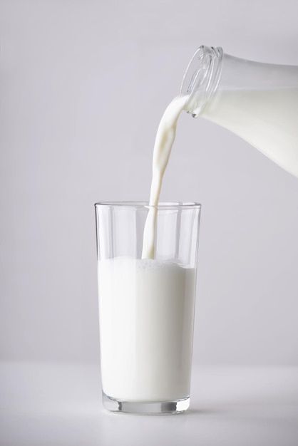 a glass filled with milk being poured into it