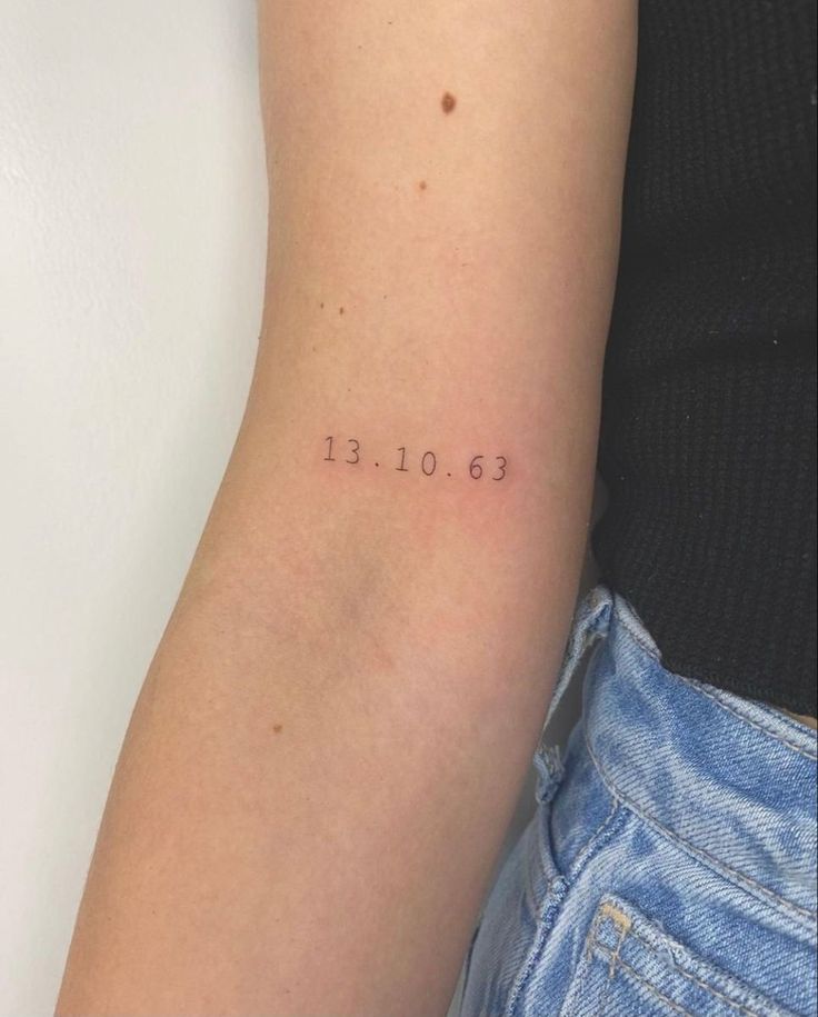 a woman's arm with the date tattooed on it