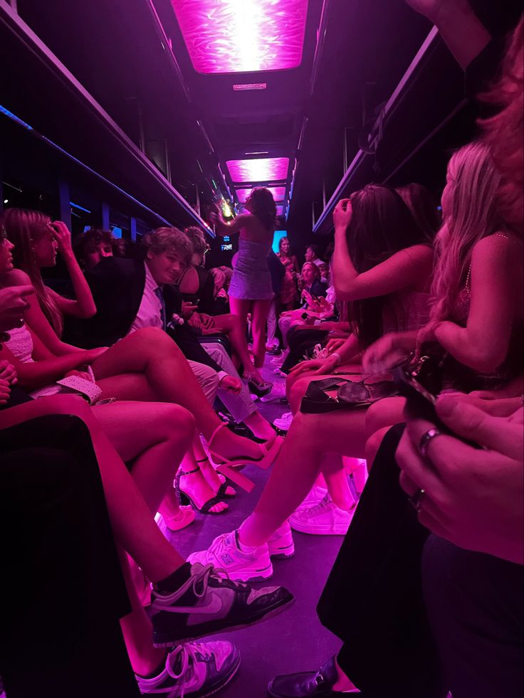 a group of people sitting next to each other in a room with neon lights on the ceiling