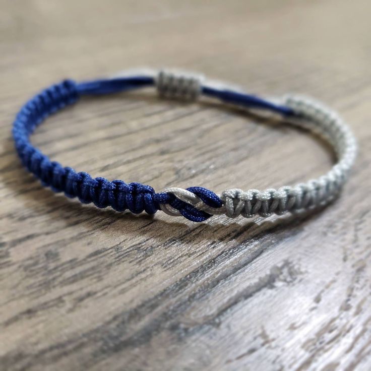 a close up of a bracelet on a wooden table with blue and white cords attached to it