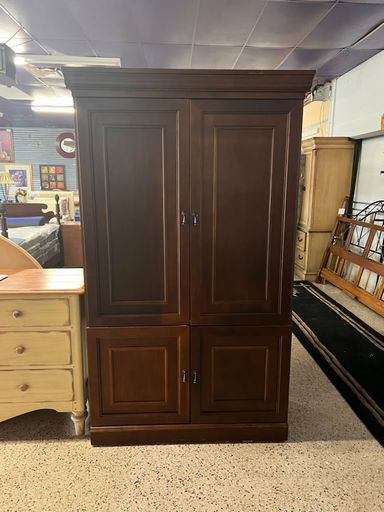 a wooden armoire sitting next to a desk in a room with lots of furniture