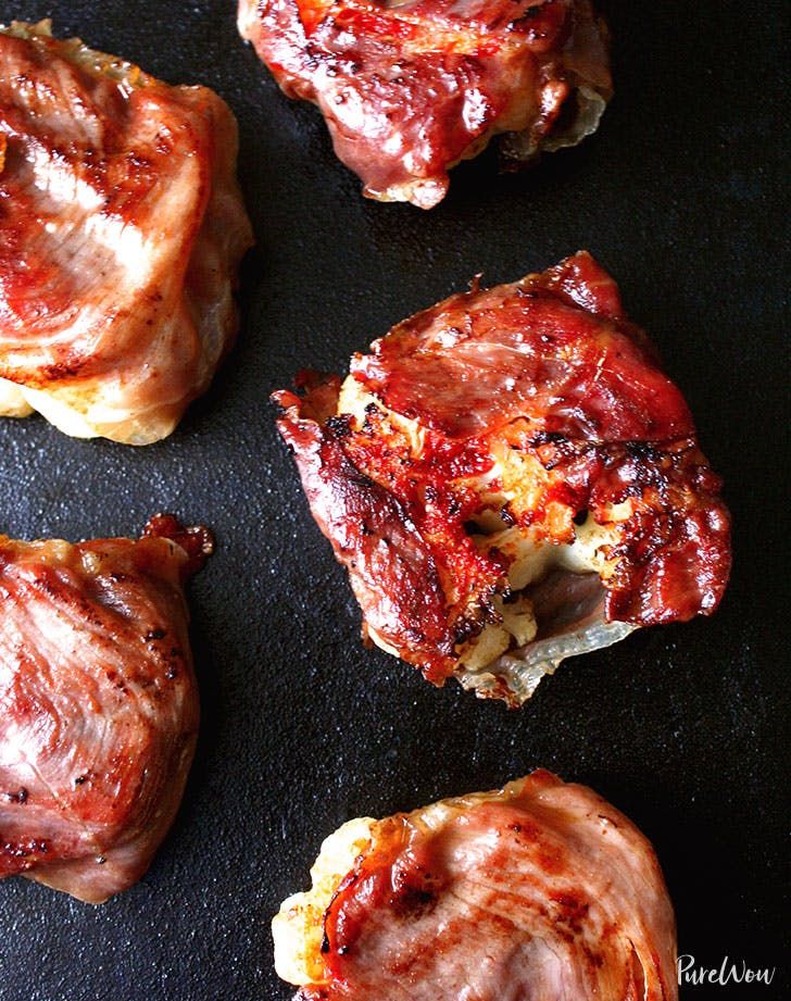 four pieces of meat sitting on top of a black surface next to some sauces