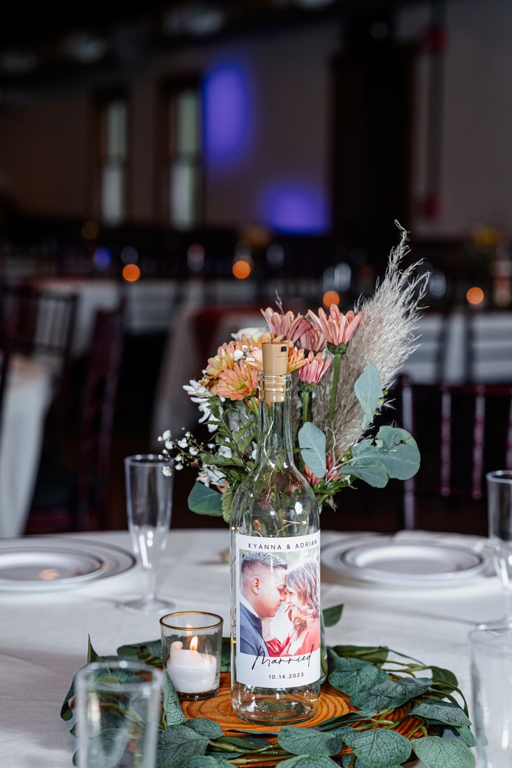 a vase with flowers and candles on a table in a restaurant or banquet hall setting