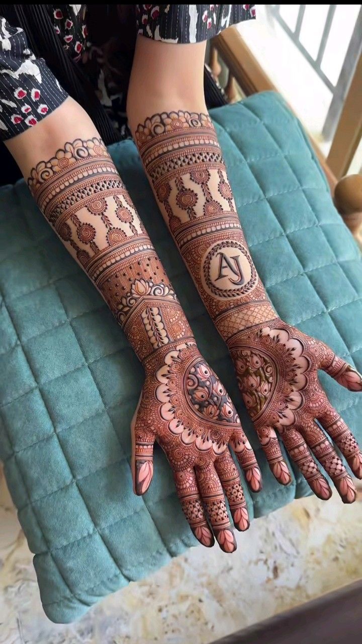 two hands with henna tattoos on them sitting on top of a blue cushion next to a window