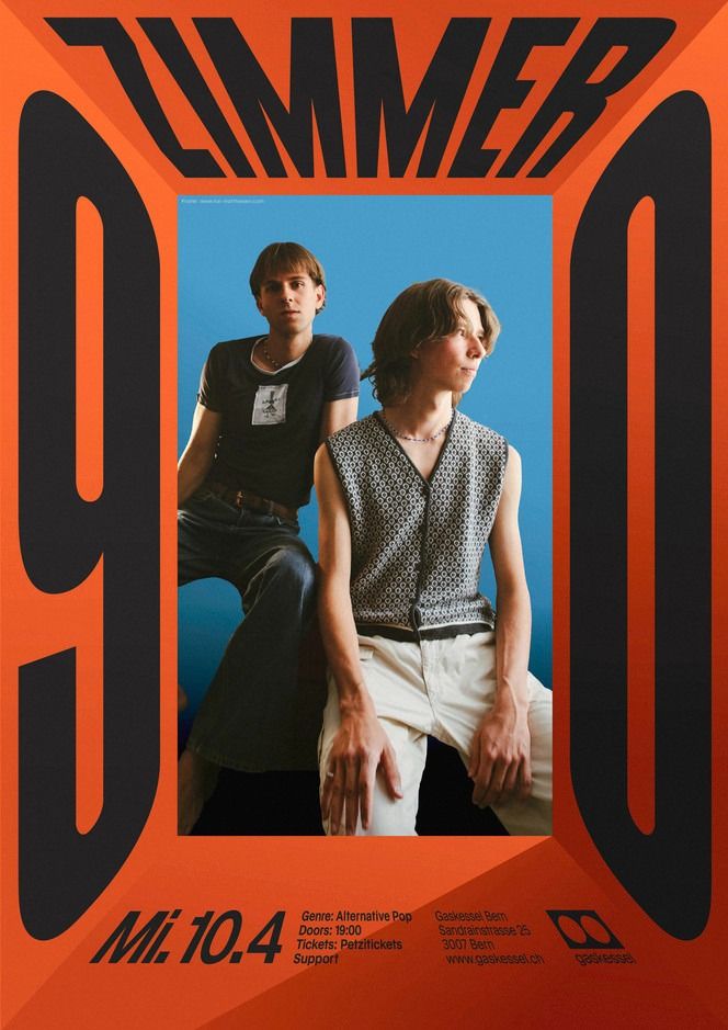 two young men sitting next to each other in front of an orange and black poster